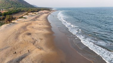 Sakin suları, kumlu sahili ve doğal tepe manzarası olan sahili, dağ arkası sakin sahili, yumuşak dalgaları ve altın saat ışığı olan sakin sahili, narin okyanus dalgaları ve arka planda tepeleri olan güzel bir sahil manzarası..