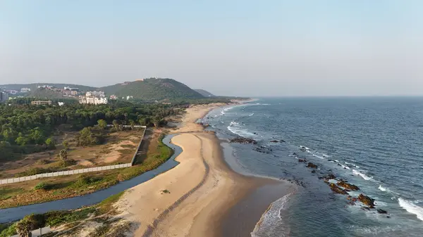 Sakin suları, kumlu sahili ve doğal tepe manzarası olan sahili, dağ arkası sakin sahili, yumuşak dalgaları ve altın saat ışığı olan sakin sahili, narin okyanus dalgaları ve arka planda tepeleri olan güzel bir sahil manzarası..