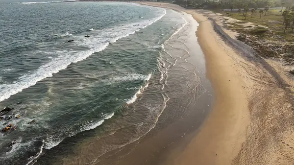 Sakin suları, kumlu sahili ve doğal tepe manzarası olan sahili, dağ arkası sakin sahili, yumuşak dalgaları ve altın saat ışığı olan sakin sahili, narin okyanus dalgaları ve arka planda tepeleri olan güzel bir sahil manzarası..