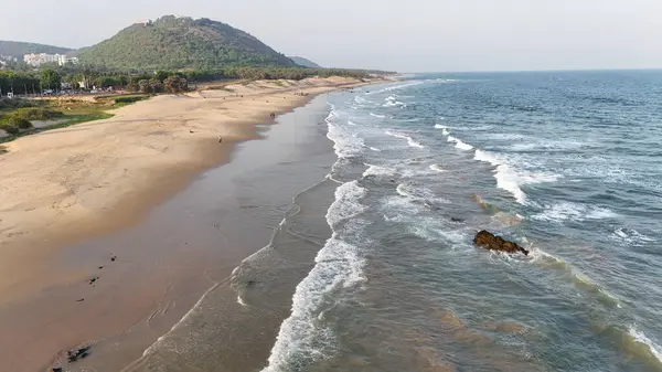 Sakin suları, kumlu sahili ve doğal tepe manzarası olan sahili, dağ arkası sakin sahili, yumuşak dalgaları ve altın saat ışığı olan sakin sahili, narin okyanus dalgaları ve arka planda tepeleri olan güzel bir sahil manzarası..