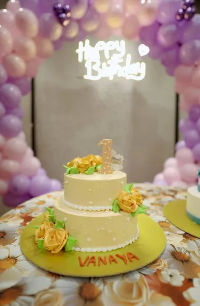 Çiçekli ve yıldızlı doğum günü pastaları, papatya desenli masa örtüsünün üstünde pembe ve mavi pastalar olan ilk doğum günü partisi düzeni, bir numaralı pastalı ikiz pastalar, pastel parti teması..