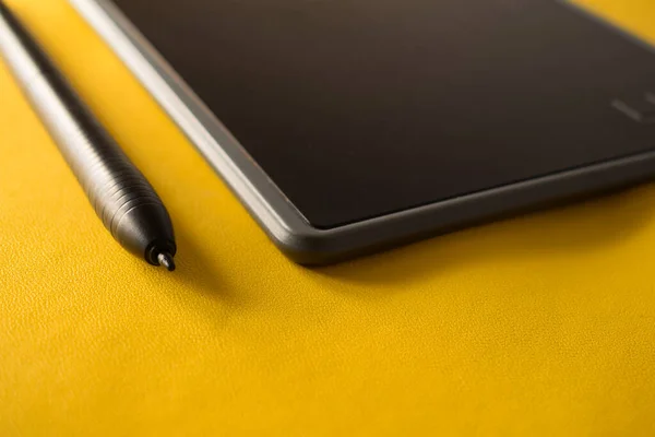 Electronic drawing pen tablet and stylus close up isolated yellow