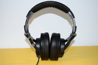 Beyaz ve sarı arka planda kablolu siyah kulaklık.