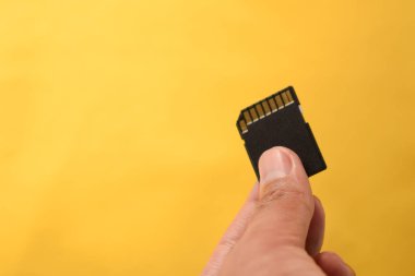 DSLR ya da sarı arkaplanda aynasız kamera için SD kart tutuyor