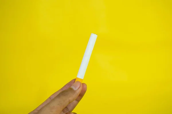Sarı Arka Planda Yapımı Bir Sigara Tutan Bir Adam — Stok fotoğraf