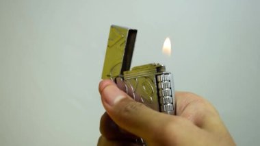Bir adam kibrit çakıyor, metalik gümüş çakmak.