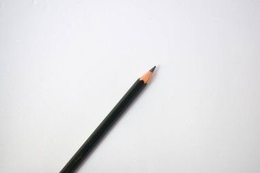 Yeşil kalem açacağı ve koyu yeşil kalemler, beyaz arka planda kalem talaşı.