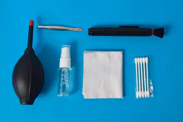 Cleaning set for camera air blower, microfiber, brush and more. Isolated on blue background