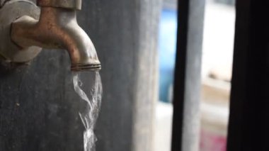 Bir musluğu kapalı ya da çitin kenarında akan suyla kapatın. Su yaşam konseptidir. El ele tutuşan silah sesleri.