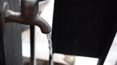 Bir musluğu kapalı ya da çitin kenarında akan suyla kapatın. Su yaşam konseptidir. El ele tutuşan silah sesleri.