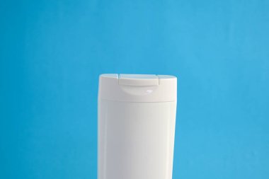 Beyaz şampuan boş. Mavi arka planlı, güzellik sigortası maketi şişesi..