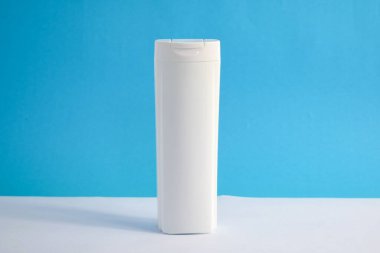 Beyaz şampuan boş. Mavi arka planlı, güzellik sigortası maketi şişesi..