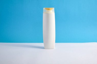 Beyaz şampuan boş. Mavi arka planlı, güzellik sigortası maketi şişesi..