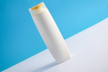 Beyaz şampuan boş. Mavi arka planlı, güzellik sigortası maketi şişesi..