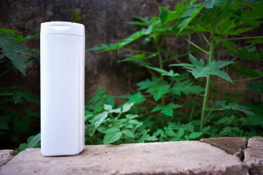 Yeşil yapraklı beyaz şişe şampuan ürünü. Çevre dostu ürün.