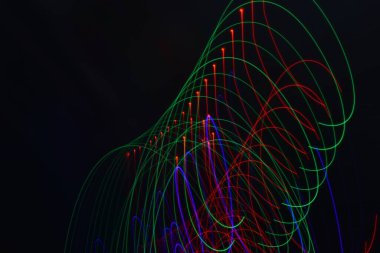 Siyah üzerine izole edilmiş uzun soluklu soyut çizgiler. Siyah arkaplanda kurşun şerit ışıklandırmasından kıvrımlı çizgiler 