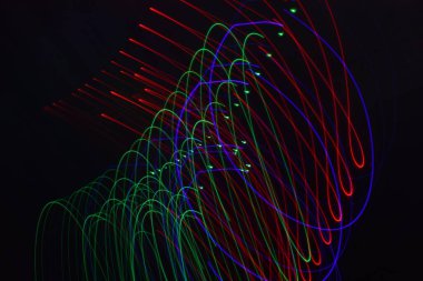 Siyah üzerine izole edilmiş uzun soluklu soyut çizgiler. Siyah arkaplanda kurşun şerit ışıklandırmasından kıvrımlı çizgiler 