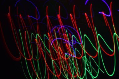 Siyah üzerine izole edilmiş uzun soluklu soyut çizgiler. Siyah arkaplanda kurşun şerit ışıklandırmasından kıvrımlı çizgiler 