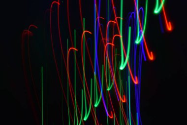 Siyah üzerine izole edilmiş uzun soluklu soyut çizgiler. Siyah arkaplanda kurşun şerit ışıklandırmasından kıvrımlı çizgiler 