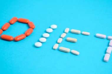 Renkli İlaç 'tan diyet kelimesi mavi arka planda izole edilmiş, vitamin, vitamin, renkli