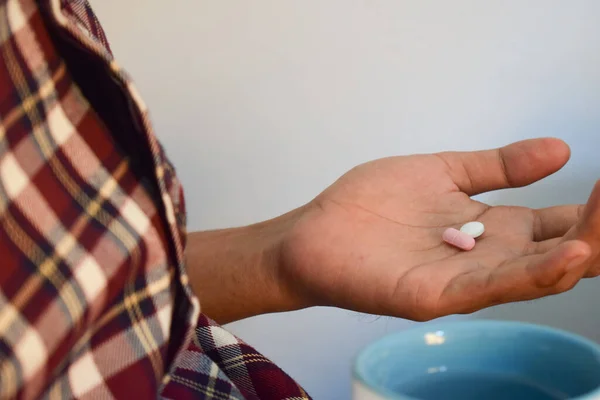 A man taking pills from bottle infront of table workspace, healthcare concept