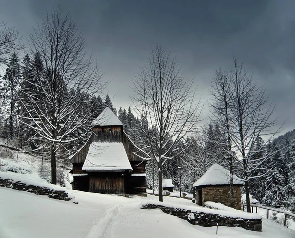 Open-air museum of the old village Zuberec, Slovakia, region Orava. The old wooden Late Gothic church of St. Alzbeta Uhorska  transferred to the open-air museum from the village of Zabrez..Gloomy winter day, snow everywhere.