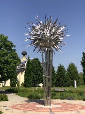 Duthe, Slovakya, 15 Mayıs 2023: Kaplıca parkındaki Güneş heykeli, arka plandaki Hıristiyan Katolik Barış Kilisesi..