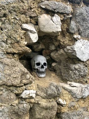 Eski bir kalenin taş duvarındaki delikte bir insan kafatası.