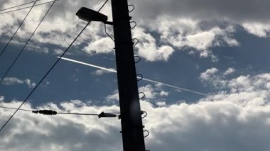 Yüksek voltaj hatlarıyla bulutlu gökyüzünde uçan patikalı bir uçak. Yüksek kalite 4k görüntü