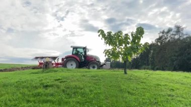 Ağacın yanındaki tarla tarlasında traktör sürüyor. Yüksek kalite 4k görüntü