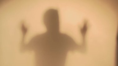 Adam perdenin arkasında siluet içinde korku gösteriyor. Yüksek kaliteli FullHD görüntüler
