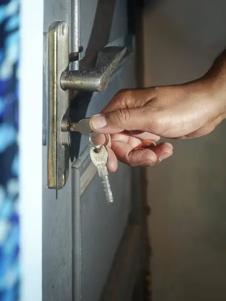 Hand opening the door lock with metal key.