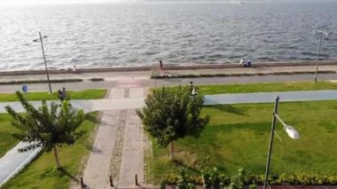 Şehrin deniz kıyısında bisiklet süren insanların insansız hava aracı görüntüsü