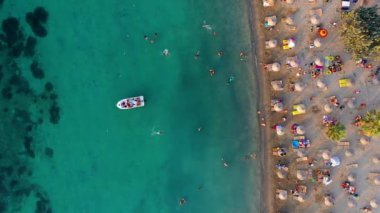 People sunbPeople sunbathing, playing and swimming in the sea, colorful umbrellas and sun loungers on the shores of Izmir on the Aegean Sea.athing, playing and swimming in the sea, colorful umbrellas