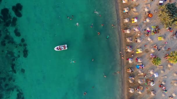 人々は日光浴をしたり 海で遊んだり泳いだり エーゲ海のイズミルの海岸でカラフルな傘やサンラウンジャーをしたりします — ストック動画