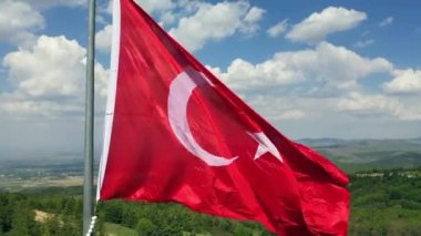 Rüzgar ve bulutlu gökyüzünde dalgalanan Türk bayrağının insansız hava aracı görüntüsü. Yüksek kaliteli FullHD görüntüler