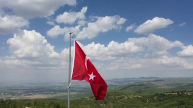 Rüzgar ve bulutlu gökyüzünde dalgalanan Türk bayrağının insansız hava aracı görüntüsü. Yüksek kaliteli FullHD görüntüler