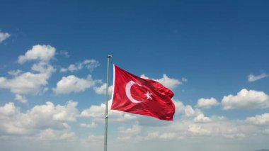 Rüzgar ve bulutlu gökyüzünde dalgalanan Türk bayrağının insansız hava aracı görüntüsü. Yüksek kaliteli FullHD görüntüler
