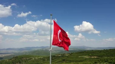 Rüzgar ve bulutlu gökyüzünde dalgalanan Türk bayrağının insansız hava aracı görüntüsü. Yüksek kaliteli FullHD görüntüler