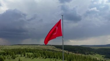 Rüzgar ve bulutlu gökyüzünde dalgalanan Türk bayrağının insansız hava aracı görüntüsü. Yüksek kaliteli FullHD görüntüler