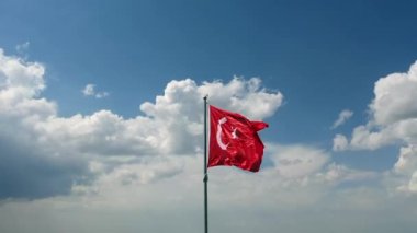 Rüzgar ve bulutlu gökyüzünde dalgalanan Türk bayrağının insansız hava aracı görüntüsü. Yüksek kaliteli FullHD görüntüler