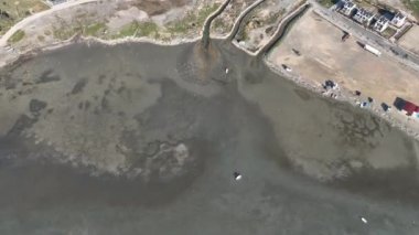 Aerial view of beautiful beach and stranded boats with pattern of sands after receding water level due to tide in aegean sea