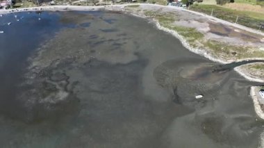 Güzel sahil manzarası ve kumlu tekneler Ege Denizi 'ndeki gelgitten dolayı su seviyesi düştükten sonra karaya oturdu.