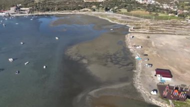 Aerial view of beautiful beach and stranded boats with pattern of sands after receding water level due to tide in aegean sea