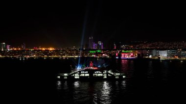 Deniz üzerinde ilerleyen feribotun hava görüntüsü ve İzmir 'in muhteşem gece manzarası. Yüksek kalite fotoğraf