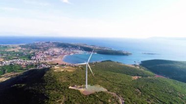 Orman bölgesinde elektrik üreten yel değirmenlerine deniz manzarası eşlik ediyor. Yüksek kalite 4k görüntü