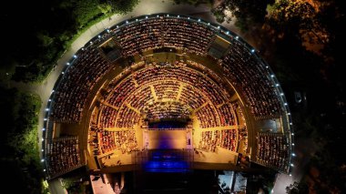 Konseri izleyen ve açık hava tiyatrosunda eğlenen insanların insansız hava görüntüsü. 