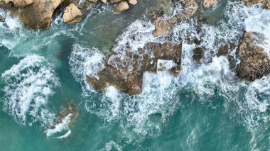 Deniz dalgalarının hava görüntüsü yüksek kalitede insansız hava aracıyla kayalara çarpıyor.