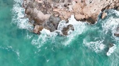 Deniz dalgalarının hava görüntüsü yüksek kalitede insansız hava aracıyla kayalara çarpıyor.