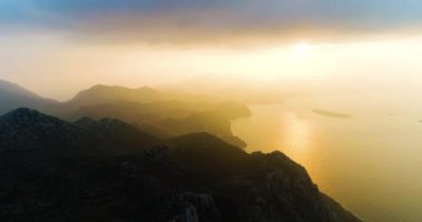 Gün doğumunda dağların üzerinde deniz ve güneş doğar. Yüksek kalite 4k görüntü